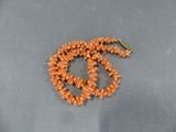 un collier composé de perles orange et orné d'un symbole de paix