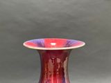 a red and purple vase sitting on a table
