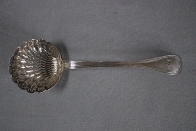 a silver spoon with a flower on it on a gray surface