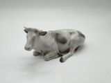 porcelain figurine of a cow laying down on a white surface