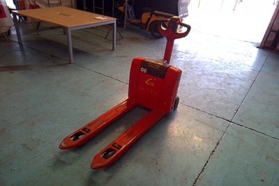 a red forklift sitting on the floor in a garage
