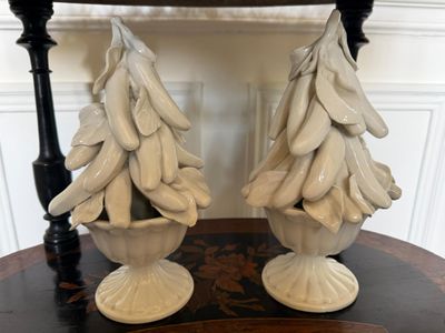 une paire de sapins de Noël en céramique blanche posés sur une table devant une chaise