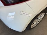 the rear end of a white car with a sticker on it ' s bumper