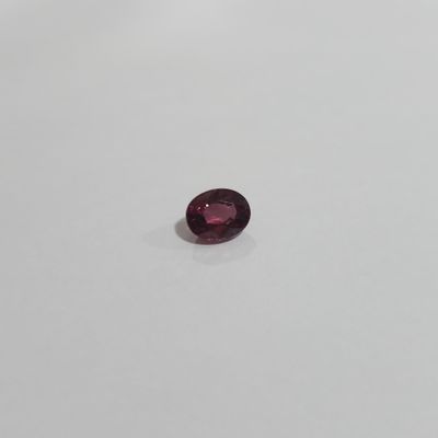 a close up of a red garnet stone on a white surface