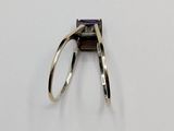 a ring with a purple stone in it on a white surface