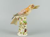 a figurine of a bird sitting on a tree stump