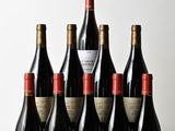 six bottles of wine are lined up on a wooden table