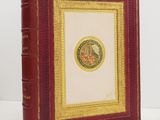 un vieux livre rouge avec une bordure dorée et l'image d'un cheval