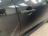 a close up of a car door handle with a person in the background