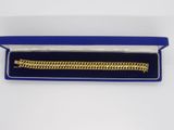 un bracelet en or dans un coffret bleu posé sur une surface blanche