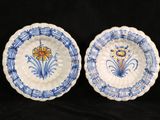 two blue and white plates with flowers on them on a black background