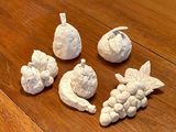 five figurines of fruit on a wooden table