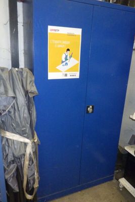 un casier bleu sur lequel est posé un sac et sur la porte duquel est accrochée une pancarte
