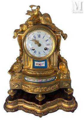une horloge en or surmontée d'un oiseau