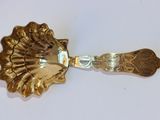 cuillère plaquée or ornée d'une tête de lion sur un fond blanc