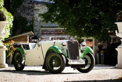 a green and white vintage car parked in front of a building