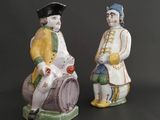 pair of ceramic figurines of a man and a woman sitting on a barrel
