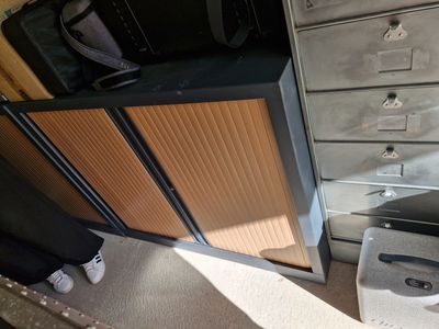 a person standing in front of a cabinet with a suitcase on top of it