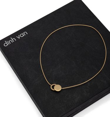 a black box with a gold necklace and a gold disc on it