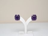 un gros plan sur une paire de boucles d'oreilles violettes posées sur un présentoir blanc