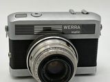 a silver camera with a black lens on a white surface