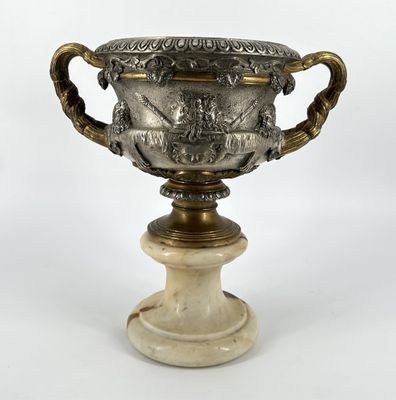 un vase ancien en argent et marbre posé sur un socle, sur fond blanc
