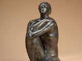 statue of a man sitting on the ground with his arms crossed