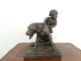 une statue en bronze représentant un garçon et un chien, posée sur une table