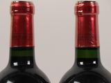 two bottles of red wine sitting next to each other on top of a table