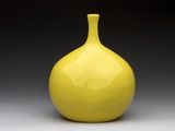 un vase jaune posé sur une table blanche