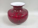 un vase rouge posé sur une table blanche