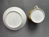 two white and gold china cups and saucers on a table