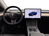 the interior of a tesla vehicle with a laptop on the dashboard