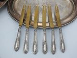 six forks and a silver plate on a table with a silver platter