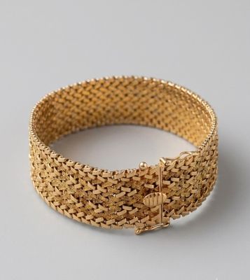 gros plan d'un bracelet en or sur une surface blanche
