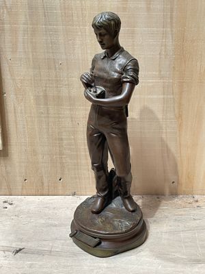 bronze statue of a boy holding a bird on a pedestal