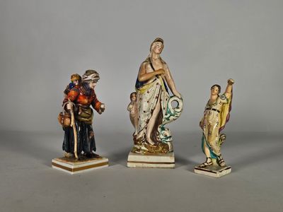trois figurines représentant des femmes et un homme avec un chien