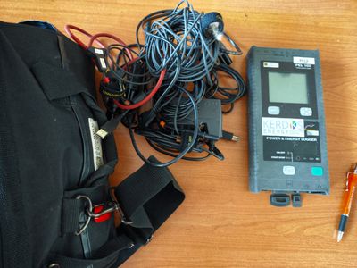 un sac noir avec des fils et un stylo à côté