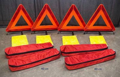 quatre panneaux d'avertissement rouges et jaunes posés sur un sol en béton