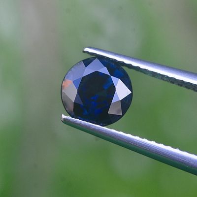 un gros plan d'un diamant bleu tenu par une pince