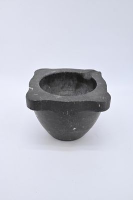 un petit bol noir muni d'une anse, posé sur une surface blanche