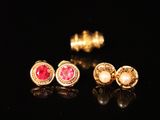 trois paires de boucles d'oreilles en or ornées de pierres roses sur un fond noir