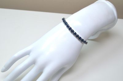une main de mannequin blanche ornée d'un bracelet en perles noires