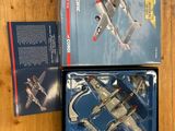 two boxed boxes with a model of a fighter plane on a wooden surface