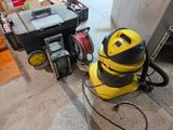 un aspirateur jaune et noir posé par terre à côté d'une boîte à outils