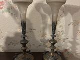 two glass vases sitting on a table in front of a floral wallpaper