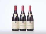 three bottles of red wine sitting on top of a white table