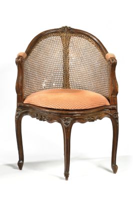 une image représentant une chaise avec un dossier en rotin et un coussin orange