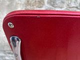 a red piece of luggage sitting on top of a chair