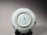 a blue and white plate on a wooden stand